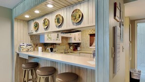 A kitchen with a central island, bar stools, and decorative plates on the wall.