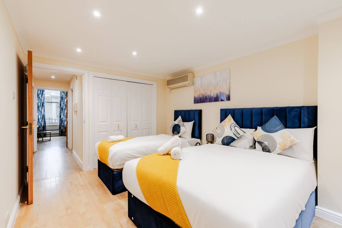 Ein Hotelzimmer mit zwei Betten, einem Flur und einer Tür zu einem anderen Raum.