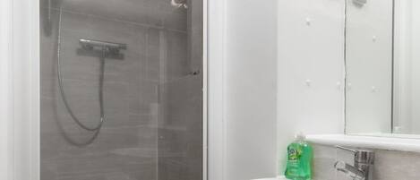 A bathroom with a glass-enclosed shower, a white sink, and a mirror.