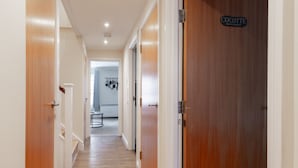 A hallway with wooden flooring and white walls, leading to a room with a door labeled "Cocotte." - Comfy Apartments in Queensway (London)