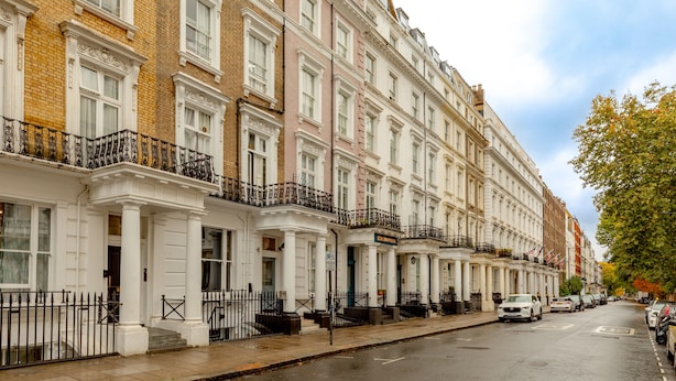A row of terraced houses with white facades and black railings. - Comfy Apartments in Queensway (London)
