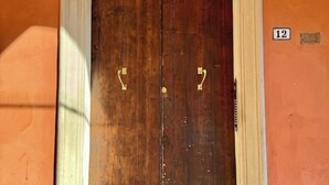 A wooden double door with brass handles, a number "12" sign on the wall to the right, and a white door frame. - Delightful House in the Center of Bologna Palazzo Storico (Bologna)