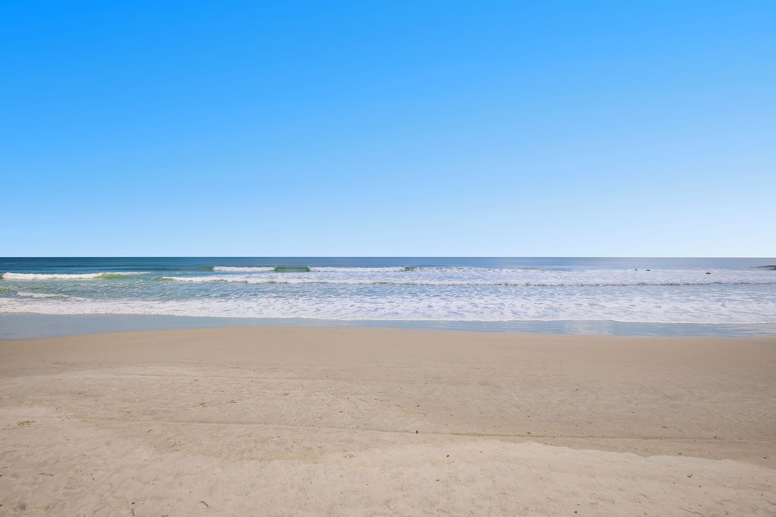 Uma praia com céu claro e mar calmo.