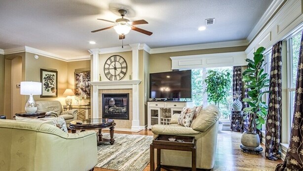 A spacious living room with a fireplace, a ceiling fan, and a television.