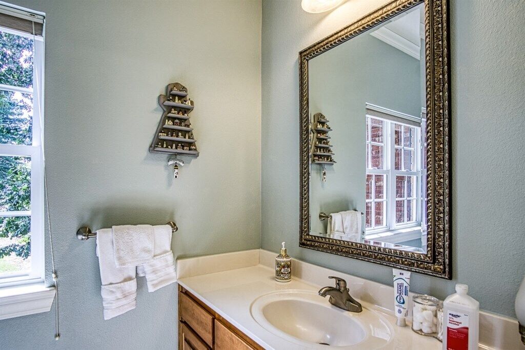 A bathroom with a white sink, a large mirror, and a towel rack.