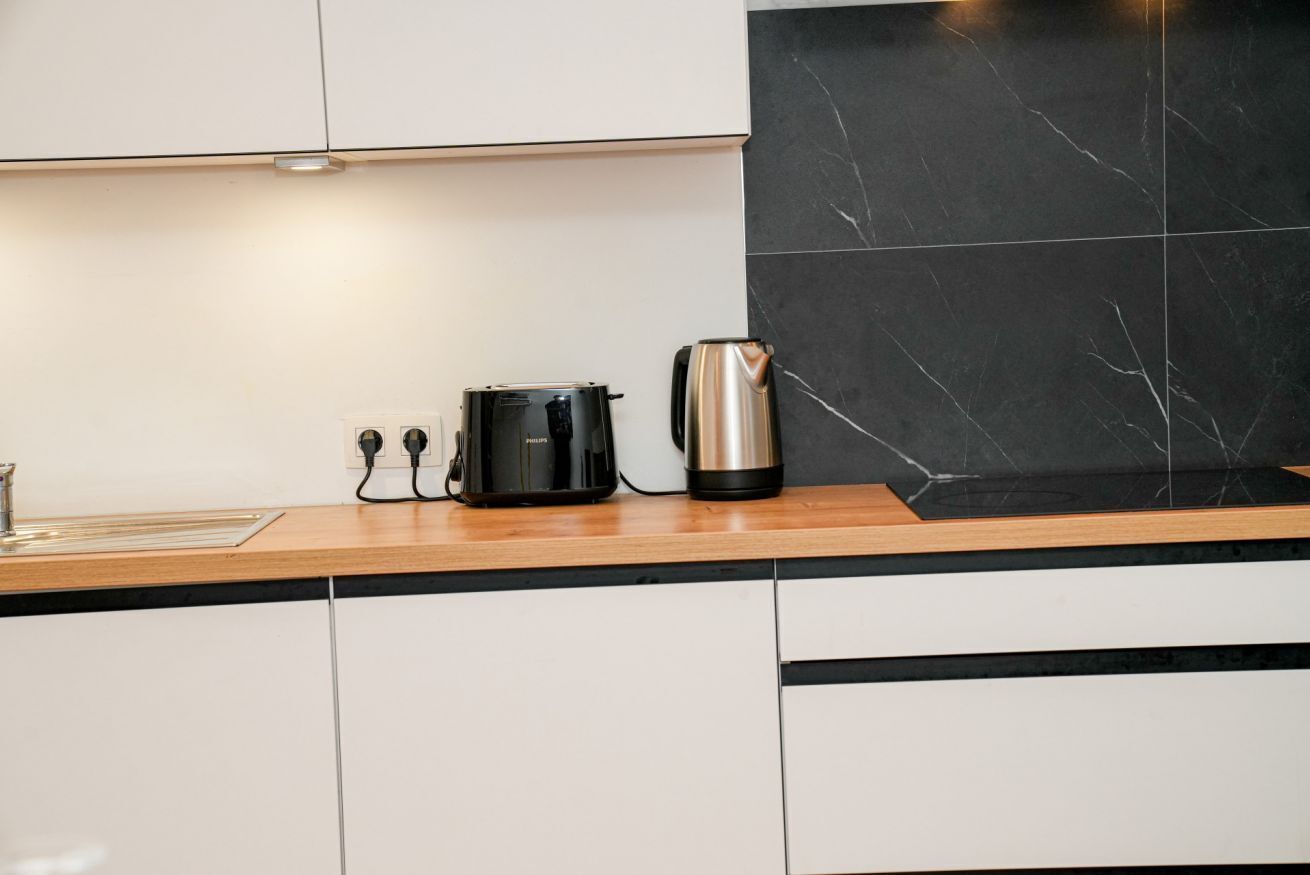 A kitchen with a black coffee maker, a black electric kettle, and a wooden countertop.