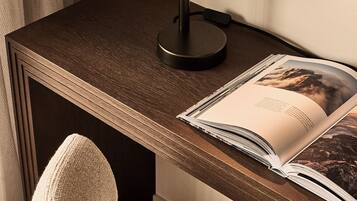 A desk with a modern desk lamp, a magazine, and a chair.