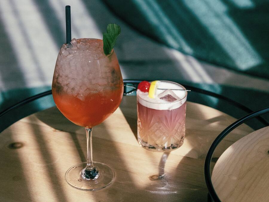Dos bebidas sobre una mesa redonda con superficie de madera.