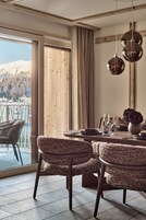 Un comedor con una mesa de madera, sillas tejidas y vistas a un paisaje nevado a través de amplios ventanales.