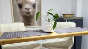 Uma área de refeições com dois bancos altos, uma mesa pequena com um laptop e uma planta em vaso.
