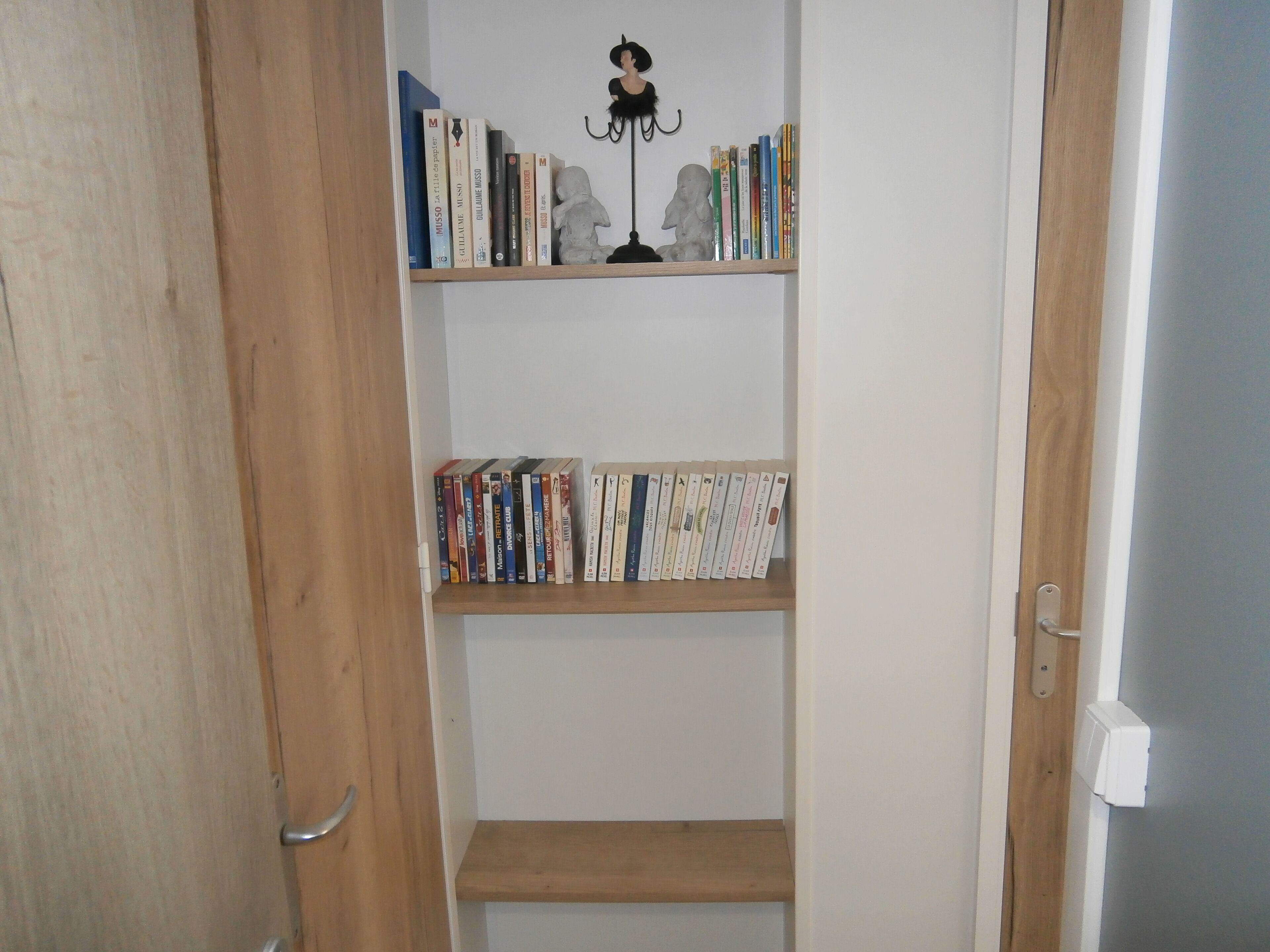 Una estantería con libros y una escultura.