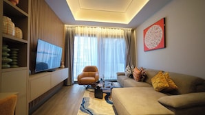 Un salon moderne avec un téléviseur à écran plat, un canapé, un fauteuil et une table basse.