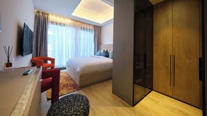 Une chambre d’hôtel moderne équipée d’un lit, d’un bureau, d’une chaise, d’une armoire et d’un téléviseur.