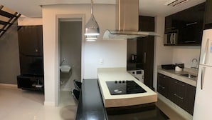 Een moderne keuken met een centraal eiland, donkere kasten, een magnetron en een koelkast.
