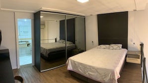 Een slaapkamer met een bed, nachtkastje en een spiegel.