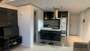 Een moderne keuken met een centraal eiland, zwarte barkrukken en een zithoek met een bank.