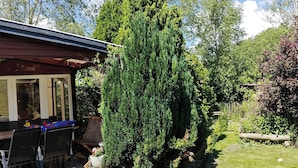 A house with a patio area, a large evergreen tree, and a garden with various plants. - Nature, tranquillity and petting zoo (Vissenbjerg)