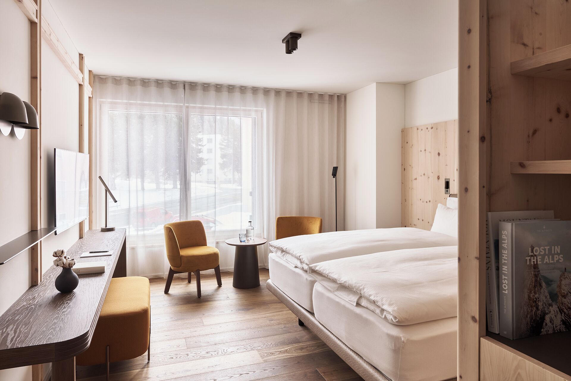 Una camera d'albergo con un letto, una scrivania, una sedia e un piccolo tavolo.