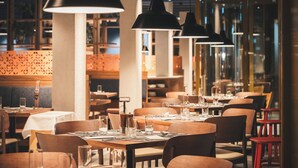 A restaurant interior with multiple dining tables, chairs, and pendant lighting. - Laudinella Apartments (St. Moritz)