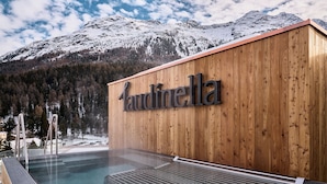 A wooden building with a sign reading "Laudinella" and a pool area with steps leading into the water. - Laudinella Apartments (St. Moritz)