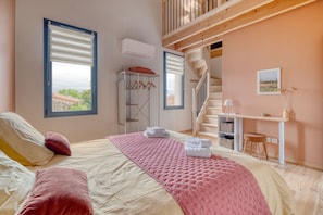 A bedroom with a bed, a desk, a chair, a wardrobe, and a staircase.