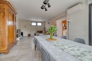 A dining area with a table set for four, a wooden cabinet, a stone wall, and a ceiling light fixture.