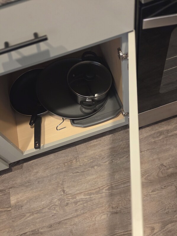 A kitchen with a white cabinet containing a black frying pan and a pot.