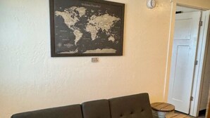 A room with a dark-colored sofa, a world map on the wall, and a door leading to another room. - Country Railroad - Wyoming Primo Managment (Green River)