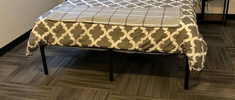 A bed with a patterned bedspread, two bedside tables with lamps, and a carpeted floor.
