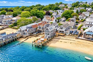 A coastal residential area with houses connected by piers to a sandy beach.