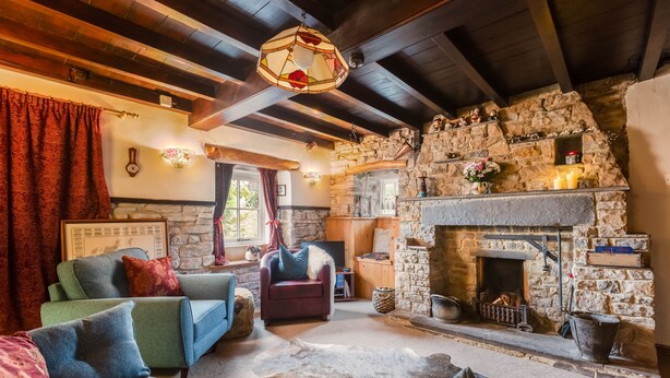 A cozy living room with a stone fireplace, wooden beams, and comfortable seating.