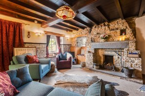 Una sala de estar acogedora con chimenea de piedra, vigas de madera y asientos cómodos.