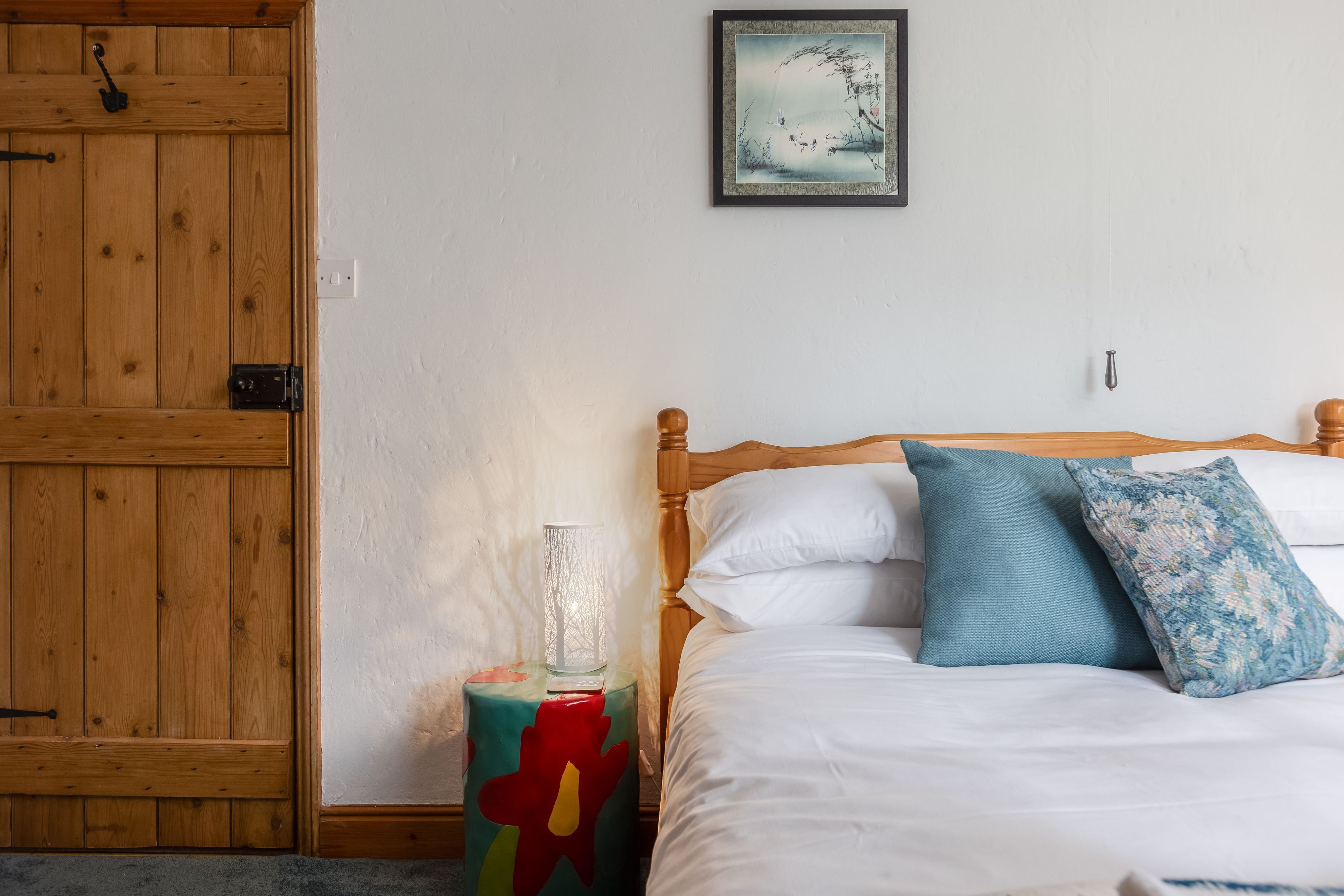 Une chambre à coucher avec un lit en bois, une literie blanche et une table de chevet colorée.