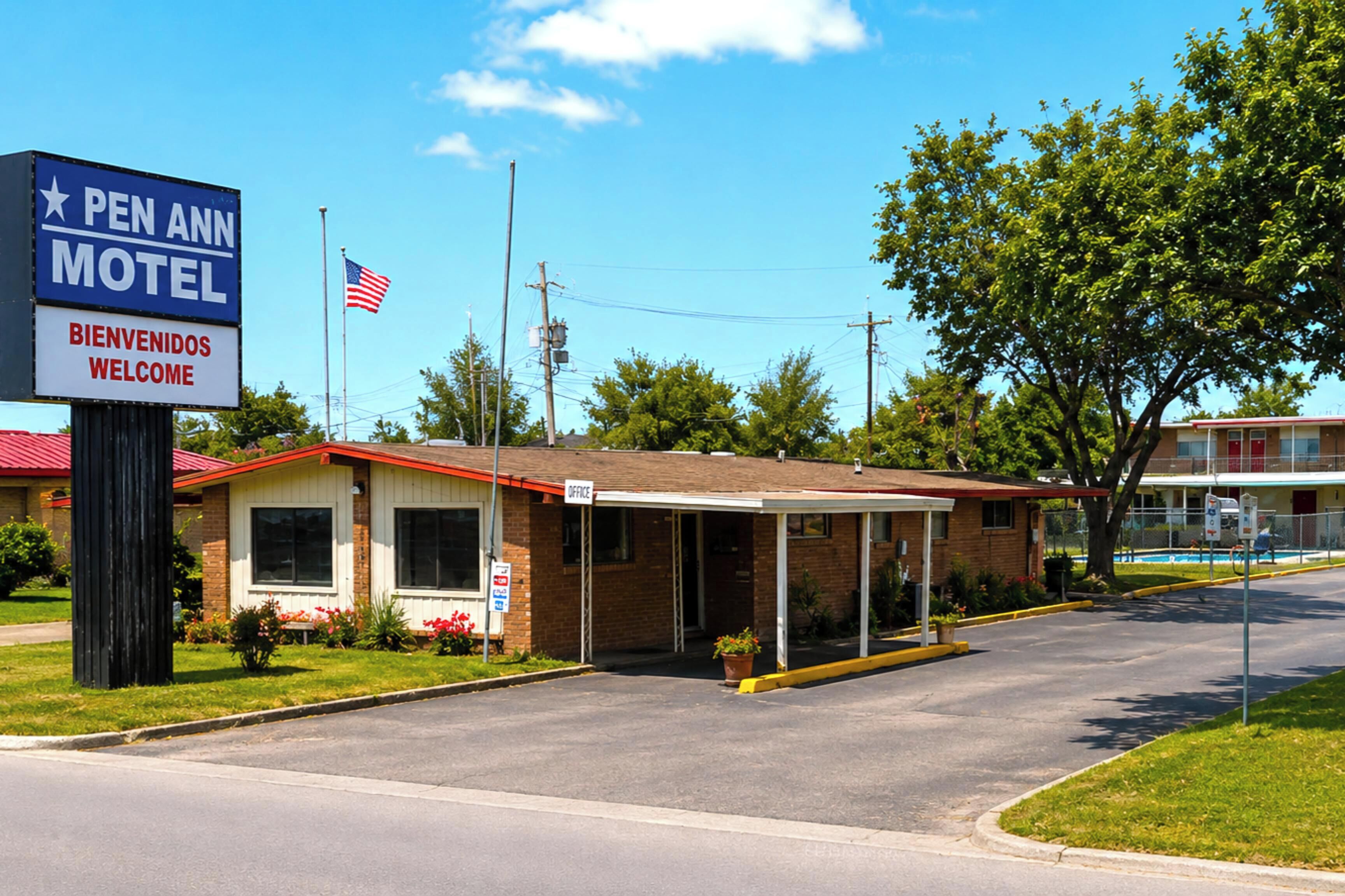 A motel with a signboard, a covered parking area, and a flag.