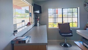 Un salón con un amplio ventanal, una silla y una barra con libros y un letrero.
