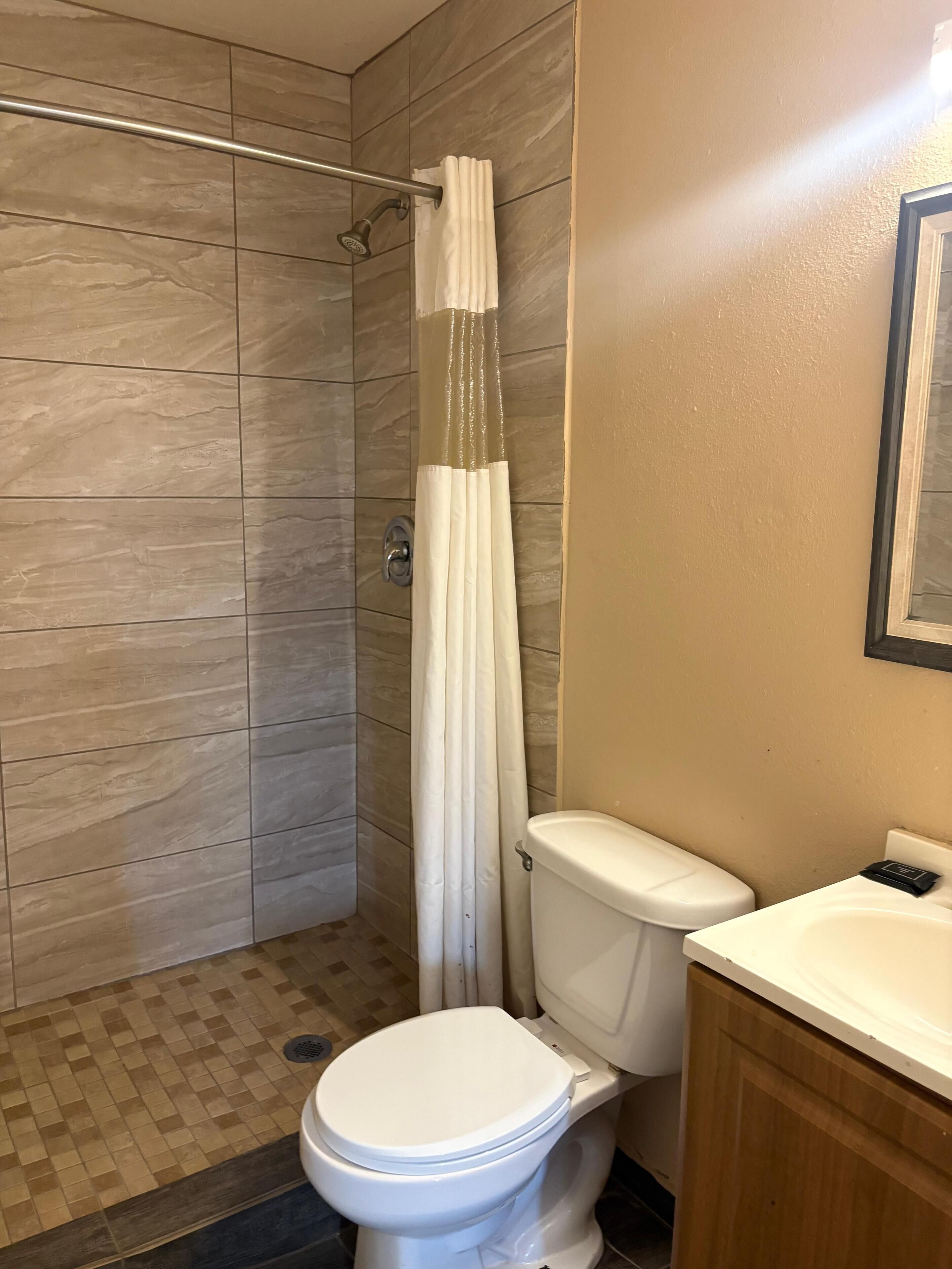Ein Badezimmer mit Dusche, Toilette und Waschbecken.