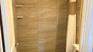 A bathroom with a shower, toilet, and a trash bin. - SE'Air Motel By Townhouse Corpus Christi / Padre Island Tx (Corpus Christi)