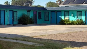 A turquoise motel with multiple doors and a parking lot. - SE'Air Motel By Townhouse Corpus Christi / Padre Island Tx (Corpus Christi)