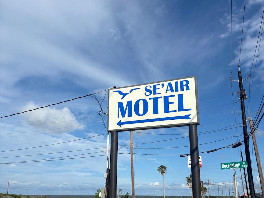 A motel sign with an arrow pointing left, a street sign for Recreation Dr, and a yellow fire hydrant.