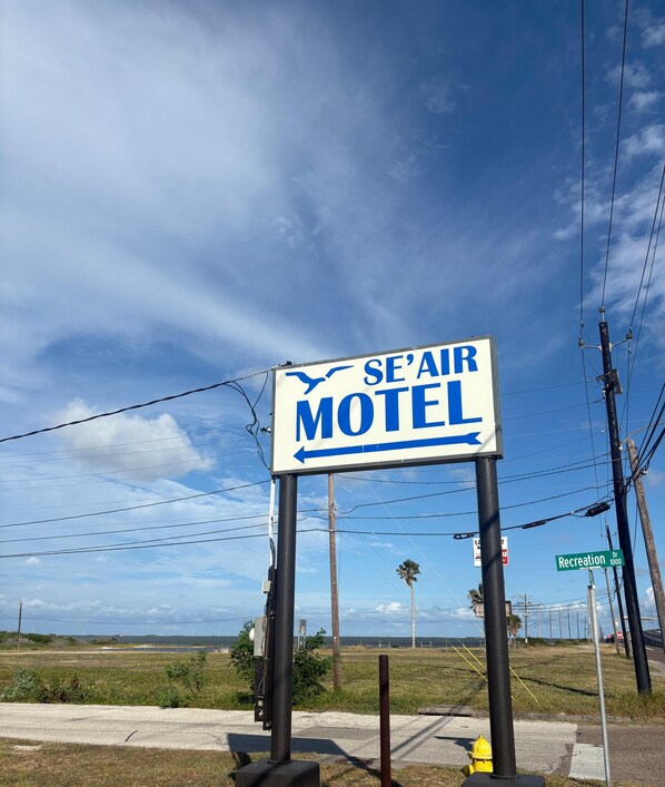 A motel sign with an arrow pointing left, a street sign for Recreation Dr, and a yellow fire hydrant.