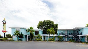 Un motel composé d’un bâtiment à deux étages, d’un parking et d’un grand arbre à l’avant.
