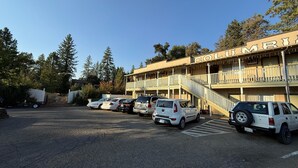 A parking lot with several cars parked in front of a building with a balcony and a staircase. - Columbia Inn Motel CA 49 (Columbia)