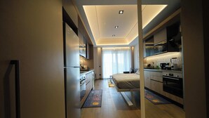 A modern hotel room with a kitchenette, a bed, and a bathroom.
