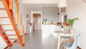 Een moderne keuken met witte kasten, een eettafel met stoelen en een houten trap.