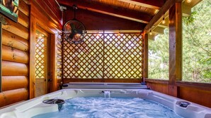 A hot tub in a wooden cabin with a lattice window and a fan above it. - Er80 - Can't Bear To Leave 2 Bedroom Cabin (Pigeon Forge)