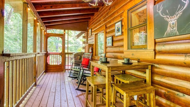 A wooden cabin with a porch, a dining table, and chairs. - Er80 - Can't Bear To Leave 2 Bedroom Cabin (Pigeon Forge)
