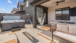 A modern outdoor patio with a hot tub, seating area, and a hanging hammock. - Red Haven 4 Bedroom Home (Washington)