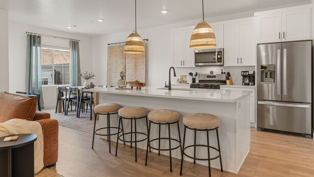 A modern kitchen with white cabinets, stainless steel appliances, and a central island with stools. - Red Haven 4 Bedroom Home (Washington)