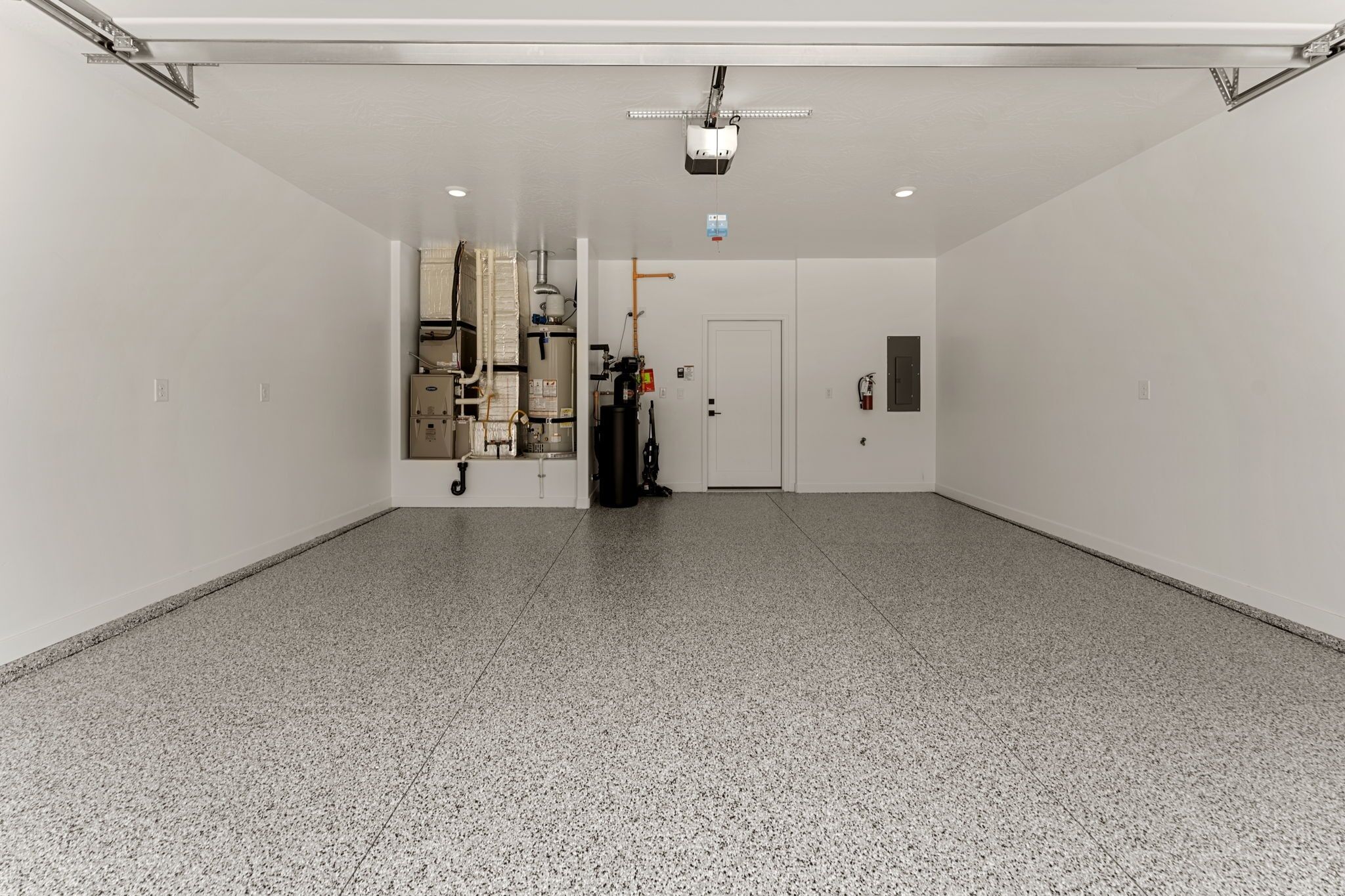 A spacious, well-lit indoor area with a tiled floor, a projector mounted on the ceiling, and a door leading to another room.