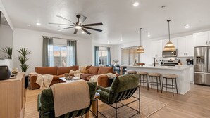 A modern kitchen with white cabinets, stainless steel appliances, and a central island with bar stools. - Red Haven 4 Bedroom Home (Washington)